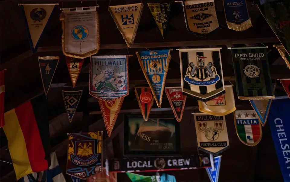 Local Pub’s timber interior, lined with football pennants from visiting supporters